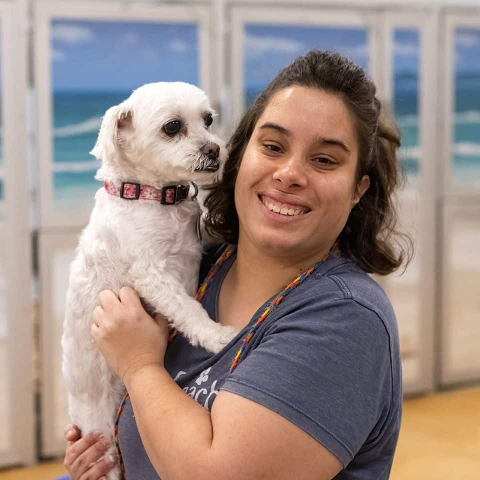dogbeach staff person smiling and holding a cute white small dog
